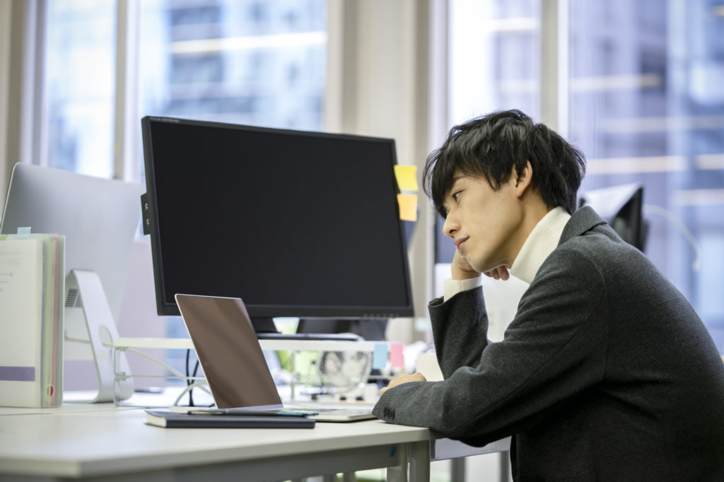 PCの前で考え込む男性のイメージ