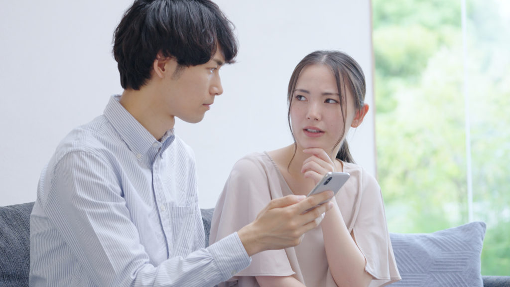 スマホを見る若い夫婦・カップル